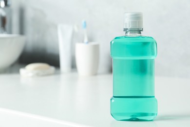 Photo of Bottle of mouthwash on white counter in bathroom. Space for text
