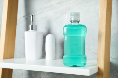 Photo of Bottle of mouthwash, soap and deodorant on shelf in bathroom, selective focus