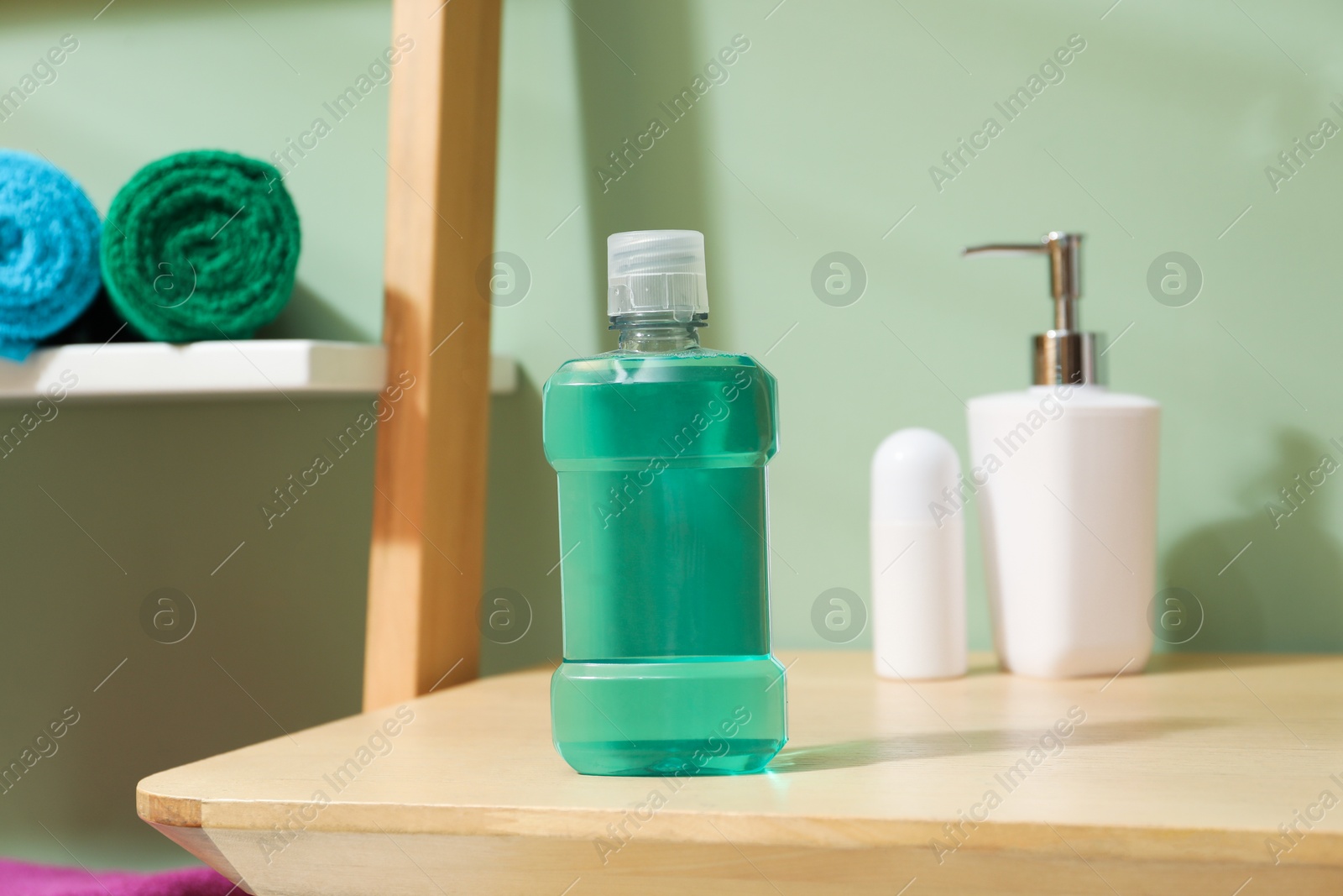Photo of Bottle of mouthwash on wooden shelf in bathroom