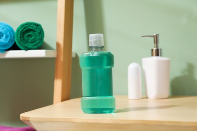 Photo of Bottle of mouthwash on wooden shelf in bathroom