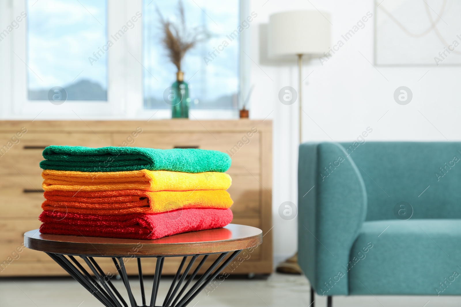 Fresh colorful terry towels on wooden table at home. Space for text Photo of Fresh colorful terry towels on wooden table at home. Space for text