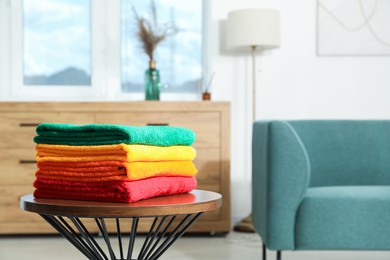 Photo of Fresh colorful terry towels on wooden table at home. Space for text