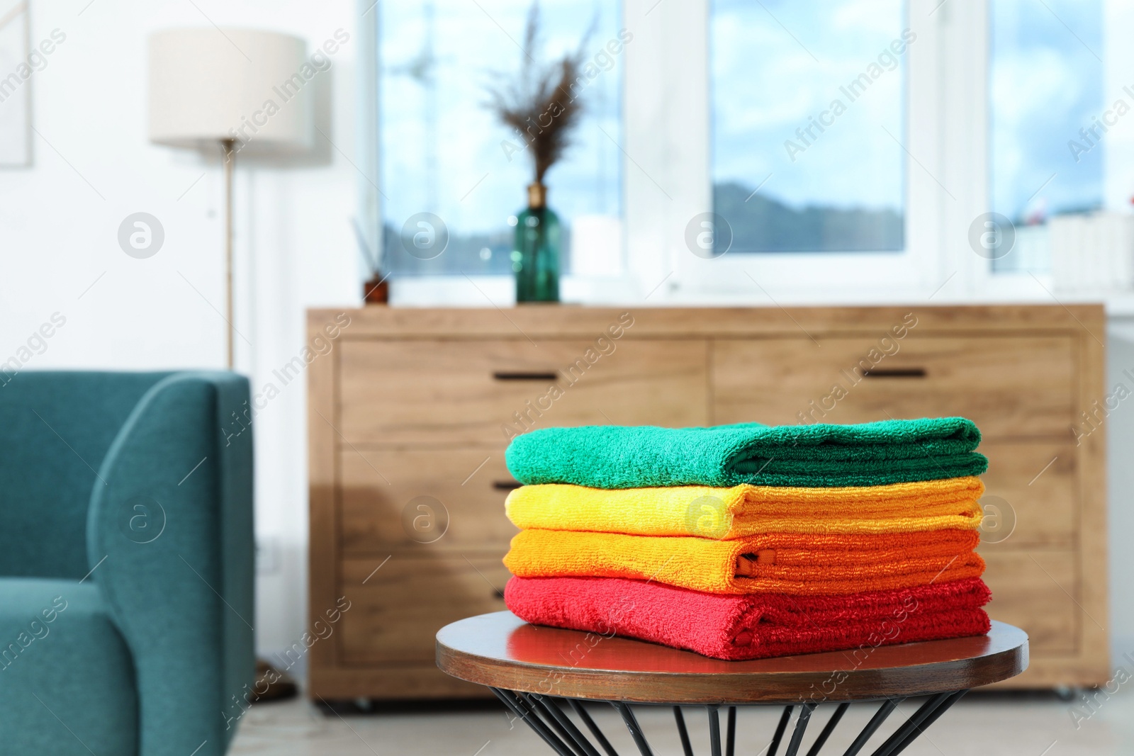 Photo of Fresh colorful terry towels on wooden table at home. Space for text