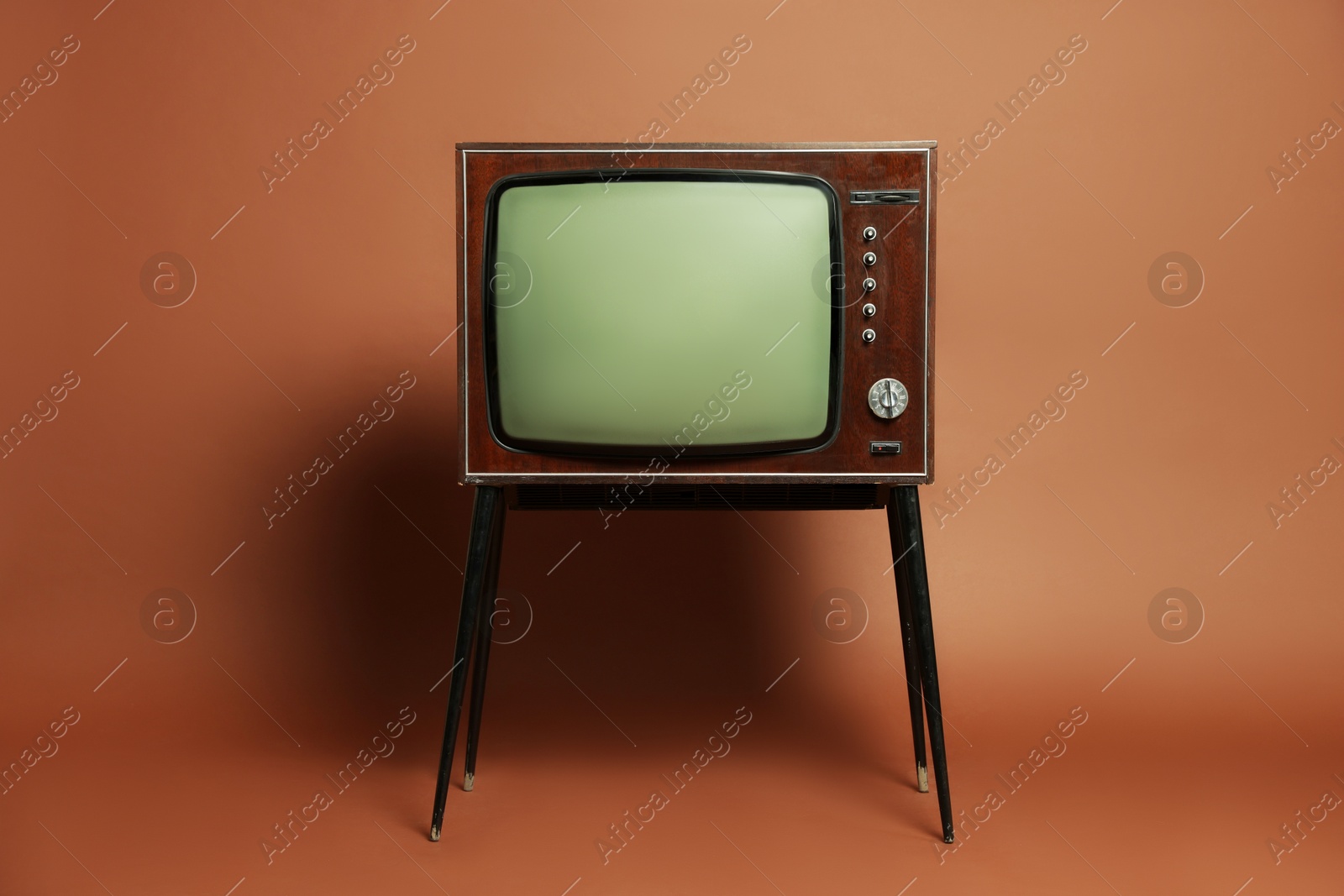 Photo of Retro TV set on stand against brown background. Used stuff