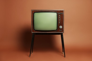 Photo of Retro TV set on stand against brown background. Used stuff