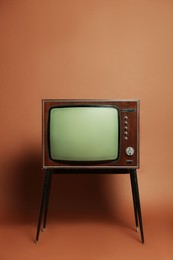 Photo of Retro TV set on stand against brown background. Used stuff