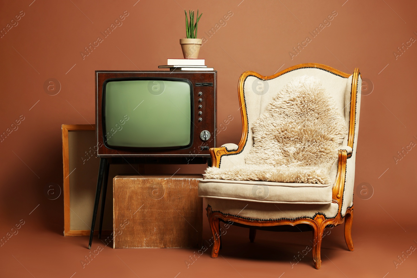 Photo of Retro TV set, armchair and other used stuff on brown background
