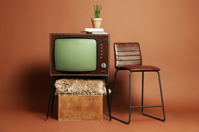 Photo of Retro TV set, bar stool and other used stuff on brown background