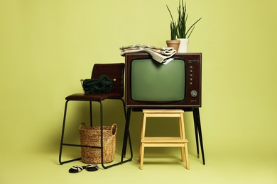 Photo of Retro TV set and other used stuff on olive background