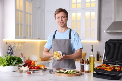 Photo of Man cooking vegetables on electric grill in kitchen