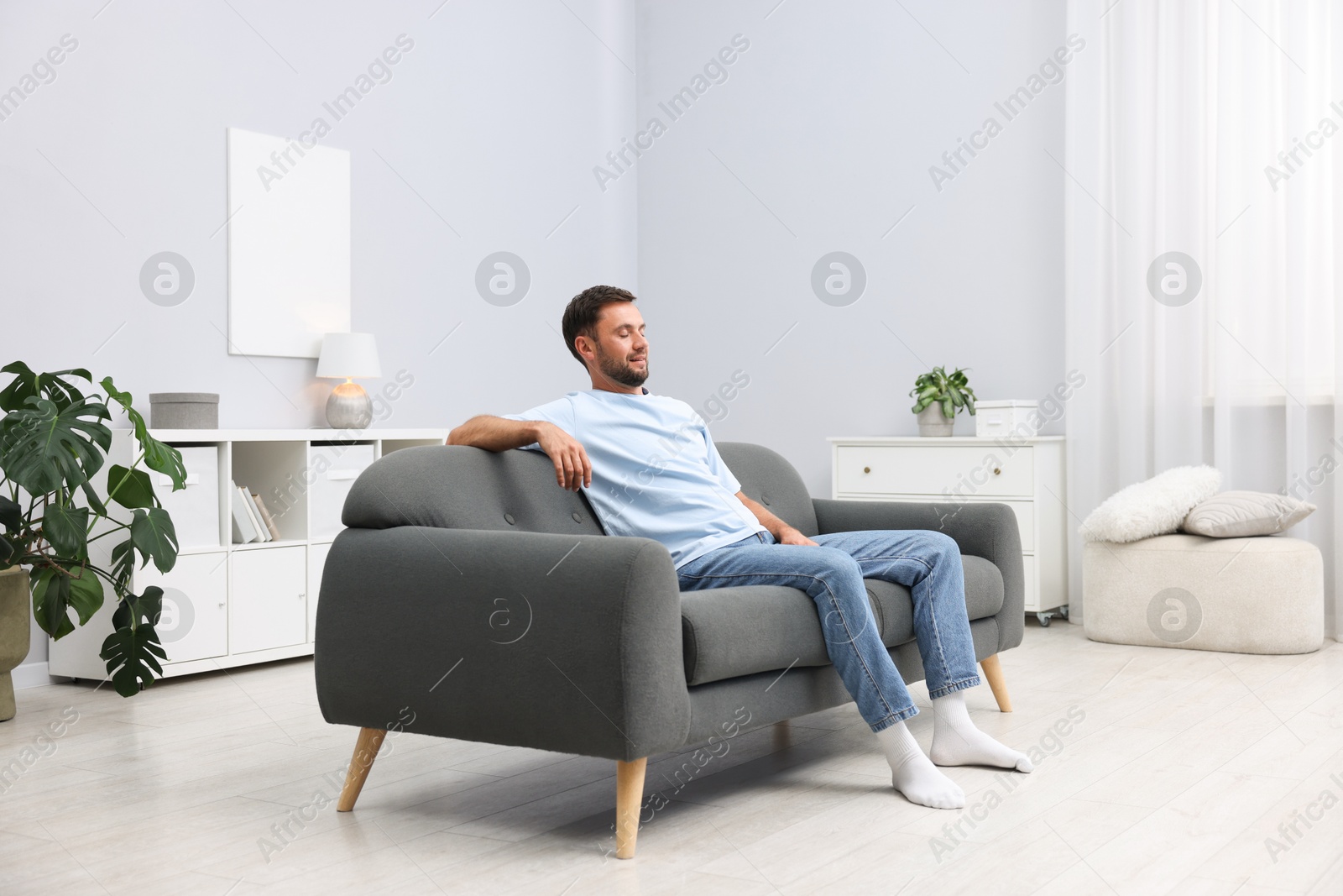 Photo of Happy man resting on sofa at home