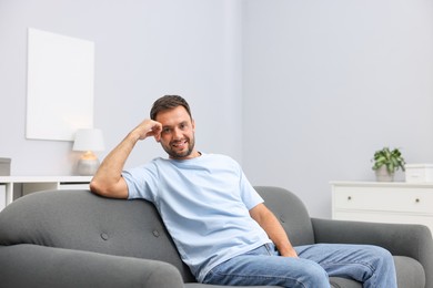 Photo of Happy man resting on sofa at home. Space for text