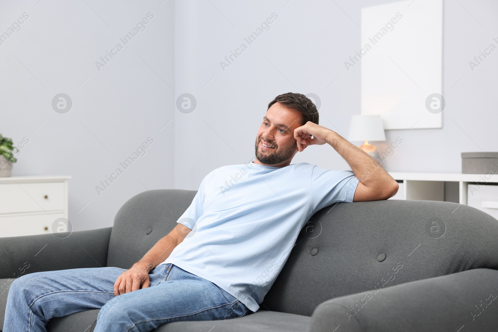 Photo of Happy man resting on sofa at home