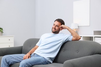 Photo of Happy man resting on sofa at home