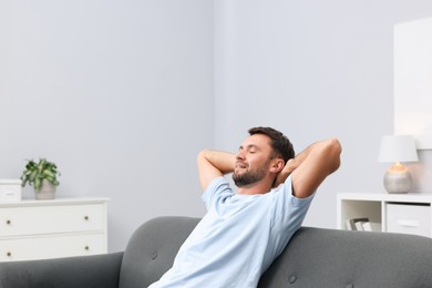 Photo of Happy man resting on sofa at home. Space for text