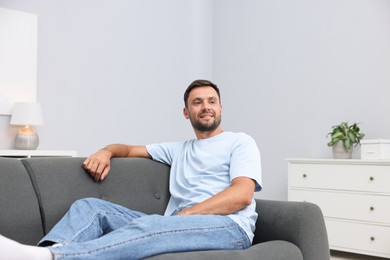 Photo of Happy man resting on sofa at home