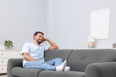 Photo of Happy man resting on sofa at home. Space for text