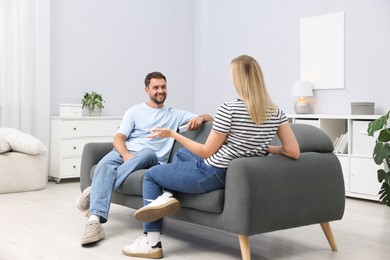 Photo of Couple with air conditioner remote control on sofa at home