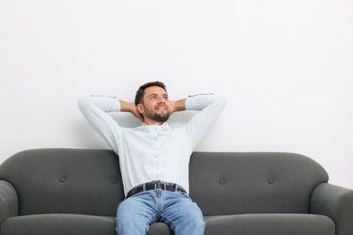 Photo of Happy man resting on sofa at home