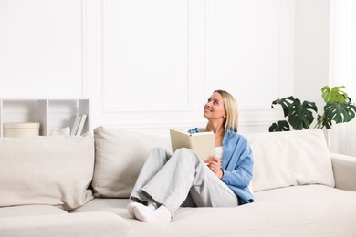 Photo of Woman reading book on sofa at home