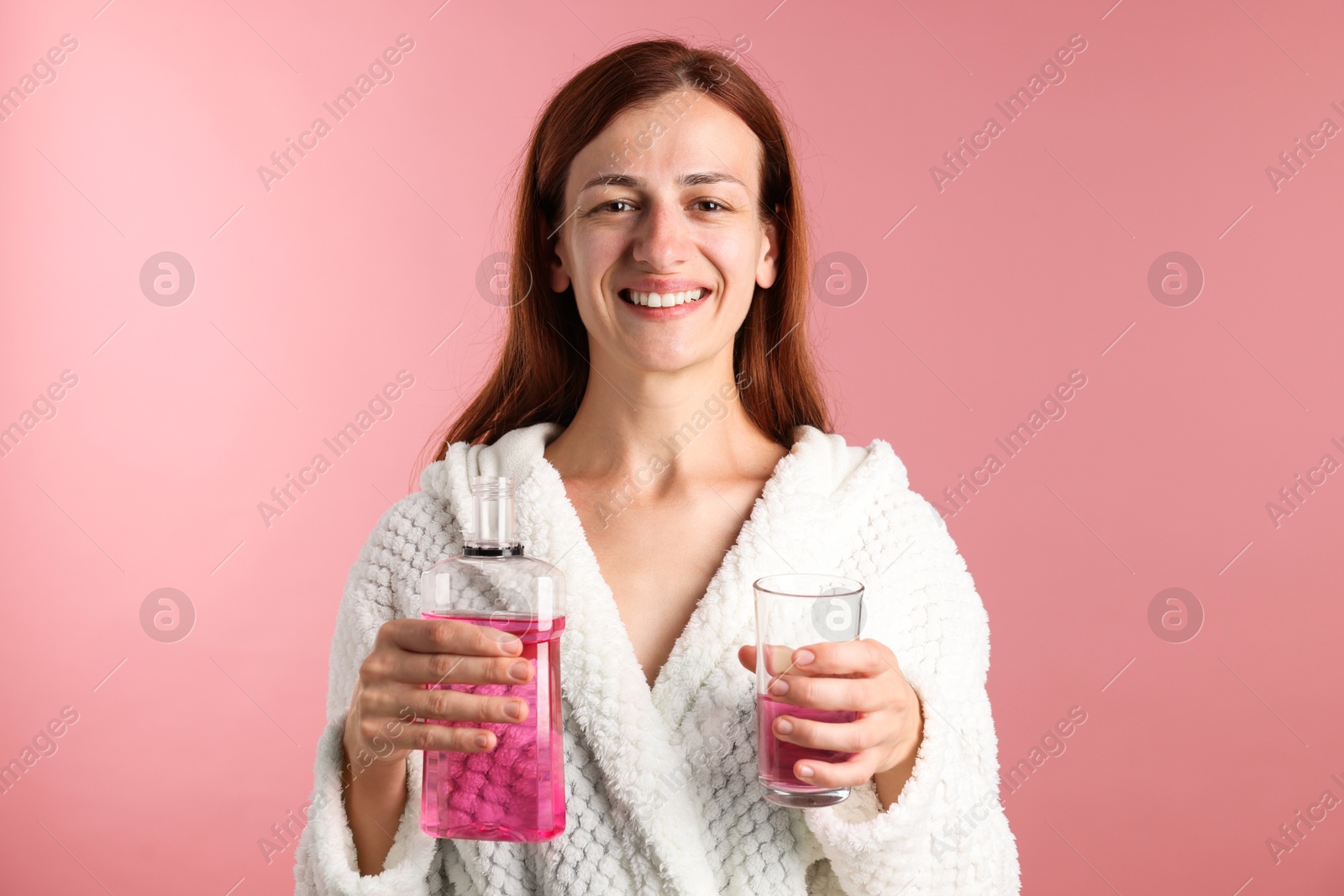 Photo of Woman rinsing mouth with mouthwash on pink background