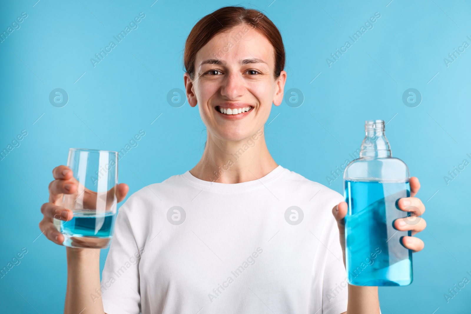 Photo of Woman rinsing mouth with mouthwash on light blue background