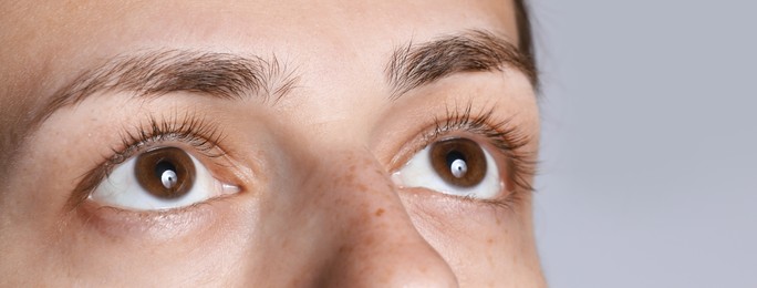 Photo of Woman with beautiful eyes on light grey background, closeup. Space for text