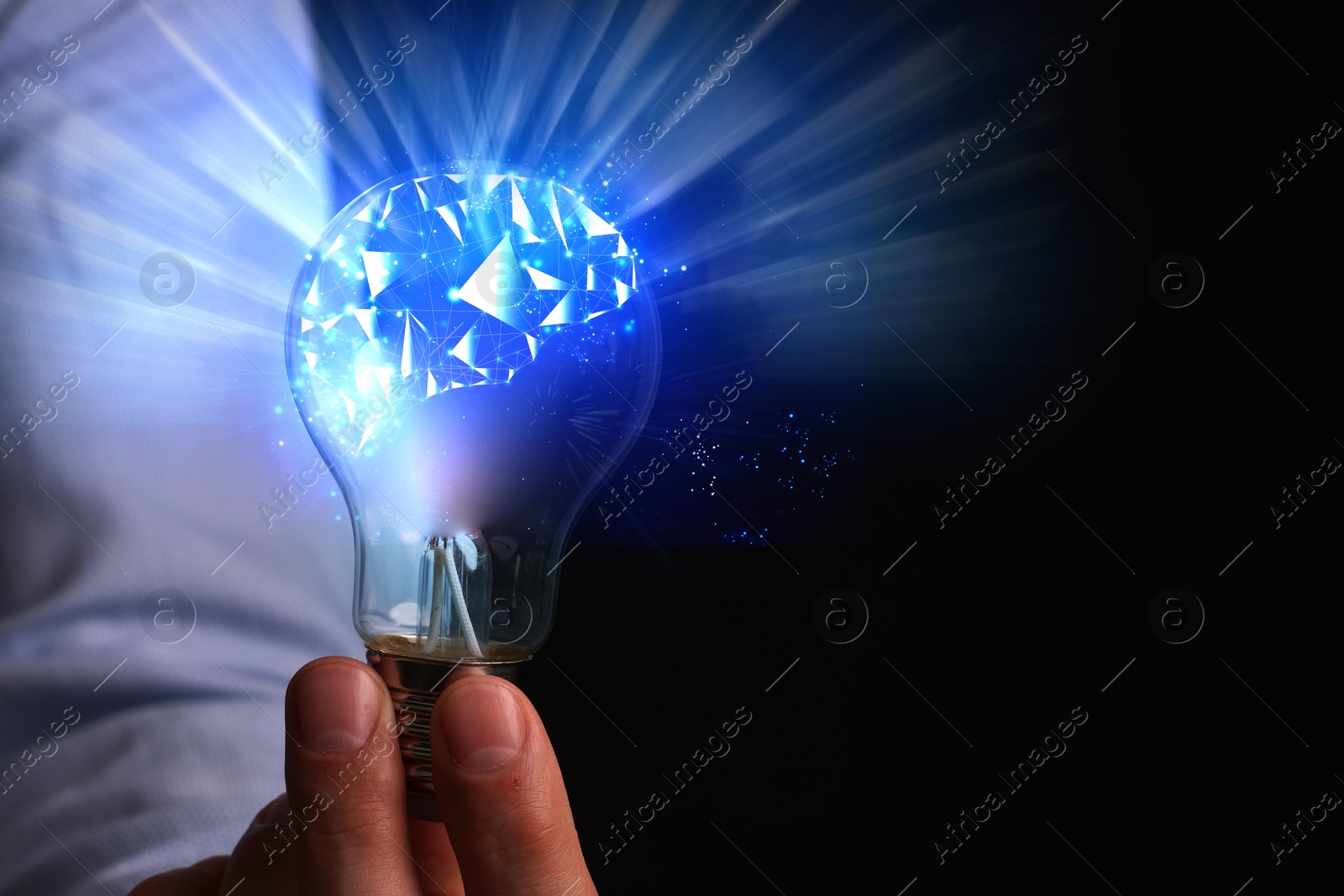 Image of Man holding light bulb with brain illustration inside against black background, closeup. Idea concept