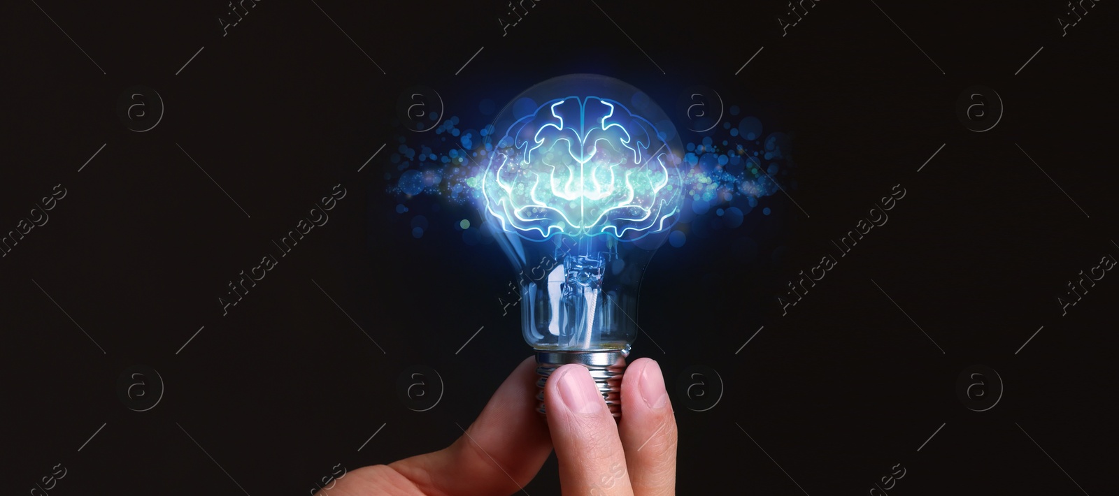 Image of Man holding light bulb with brain illustration inside against black background, closeup. Idea concept