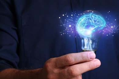 Image of Man holding light bulb with brain illustration inside, closeup. Idea concept
