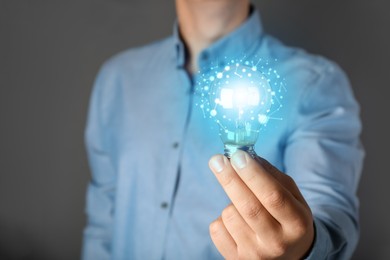 Image of Man holding light bulb with brain inside against grey background, closeup. Idea concept