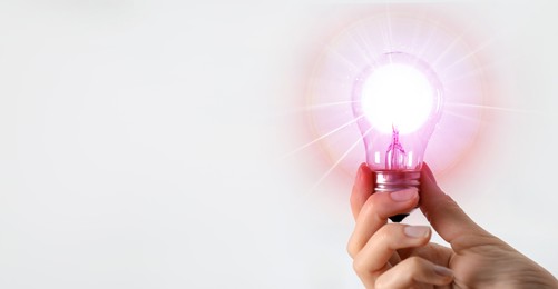 Image of Woman holding glowing light bulb against white background, closeup. Idea concept
