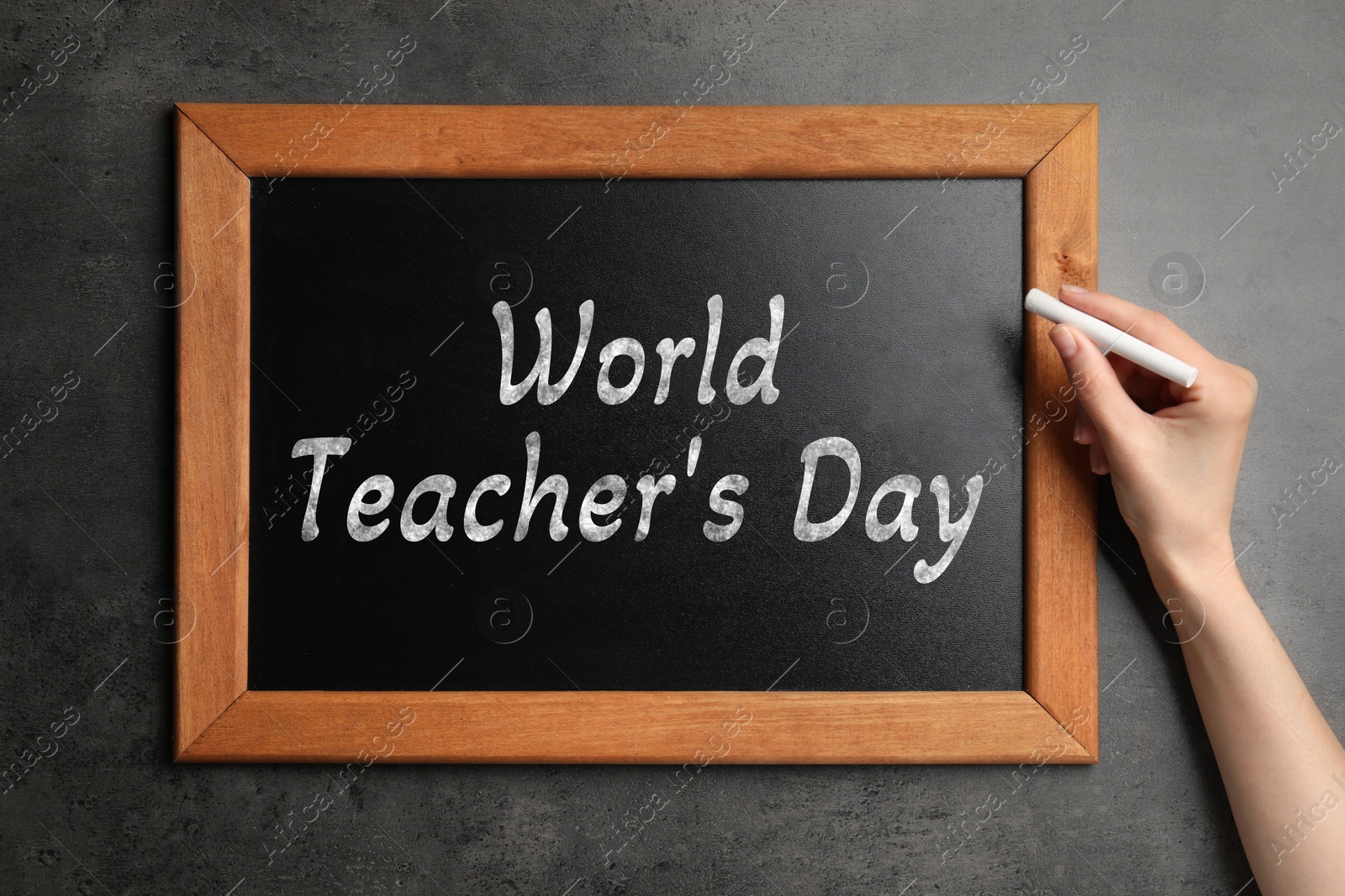 Image of Happy Teacher's Day greeting card. Woman writing text on small blackboard, closeup