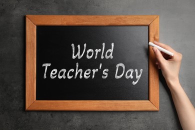 Image of Happy Teacher's Day greeting card. Woman writing text on small blackboard, closeup