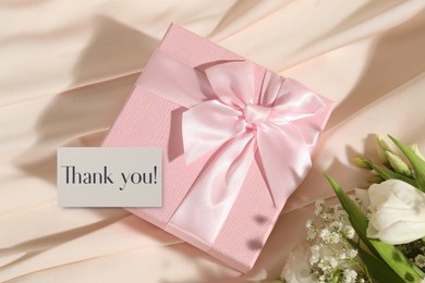 Image of Thank you card, gift box and flowers on beige fabric
