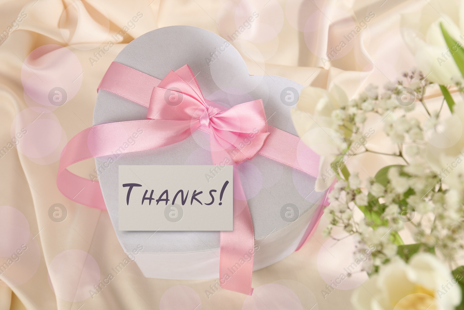 Image of Thanks card, gift box and flowers on beige fabric, bokeh effect