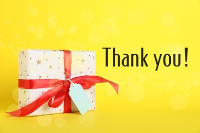 Image of Thank you card design with gift box on yellow background. Bokeh effect