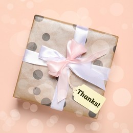 Image of Thanks tag attached to gift box on dark beige background. Bokeh effect