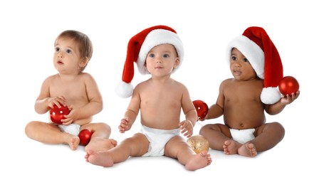 Image of Cute babies in Christmas balls and Santa hats on white background