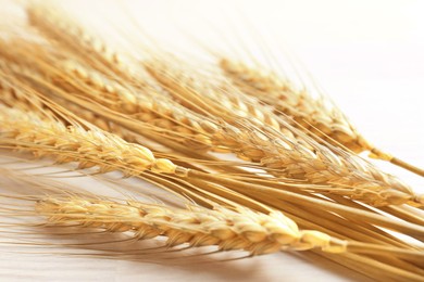 Image of Golden ears of wheat on white wooden table, closeup