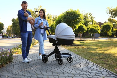 Photo of Happy parents walking with their baby in park on sunny day