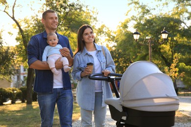 Photo of Happy parents walking with their baby in park on sunny day