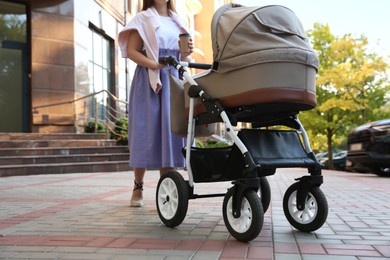 Photo of Young mother walking with her baby in stroller outdoors, closeup