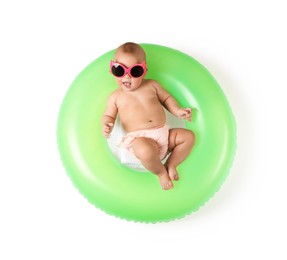 Photo of Cute little baby in sunglasses with inflatable ring on white background, top view