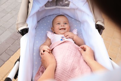Photo of Mother covering her baby with blanket in stroller, closeup