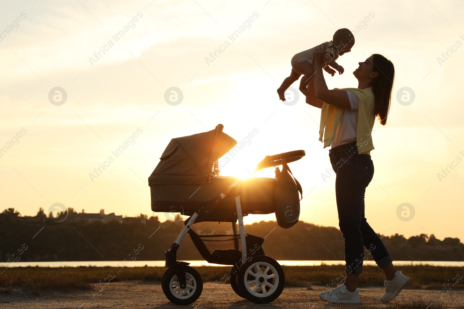Photo of Happy mother with baby near river at sunset