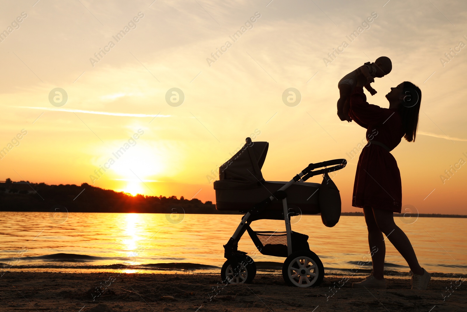 Photo of Happy mother with baby near river at sunset