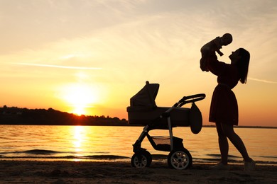 Photo of Happy mother with baby near river at sunset