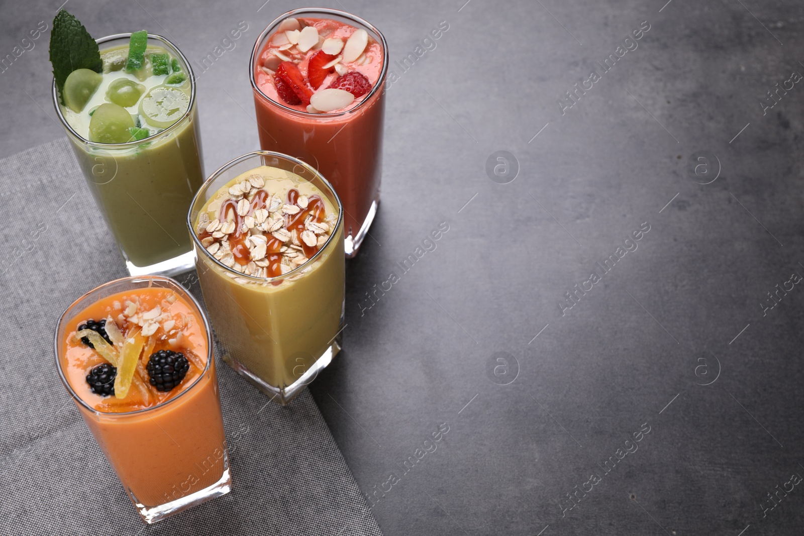 Photo of Many different delicious smoothies on grey table, above view. Space for text