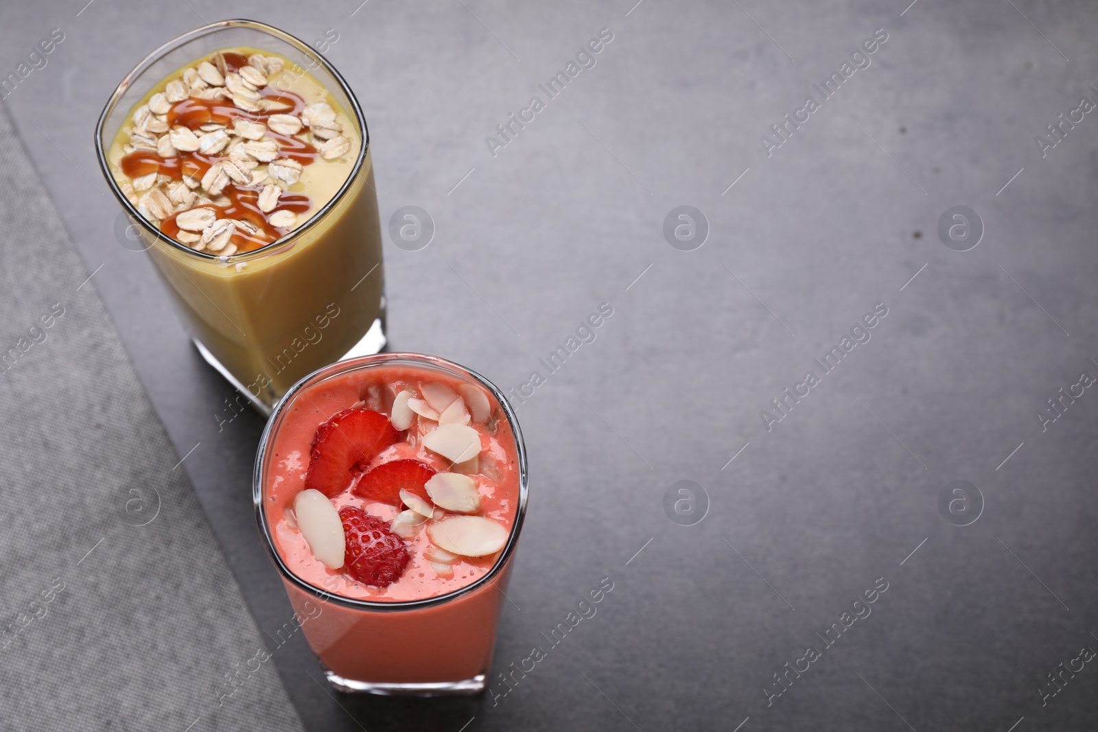 Photo of Different delicious smoothies on grey table, above view. Space for text
